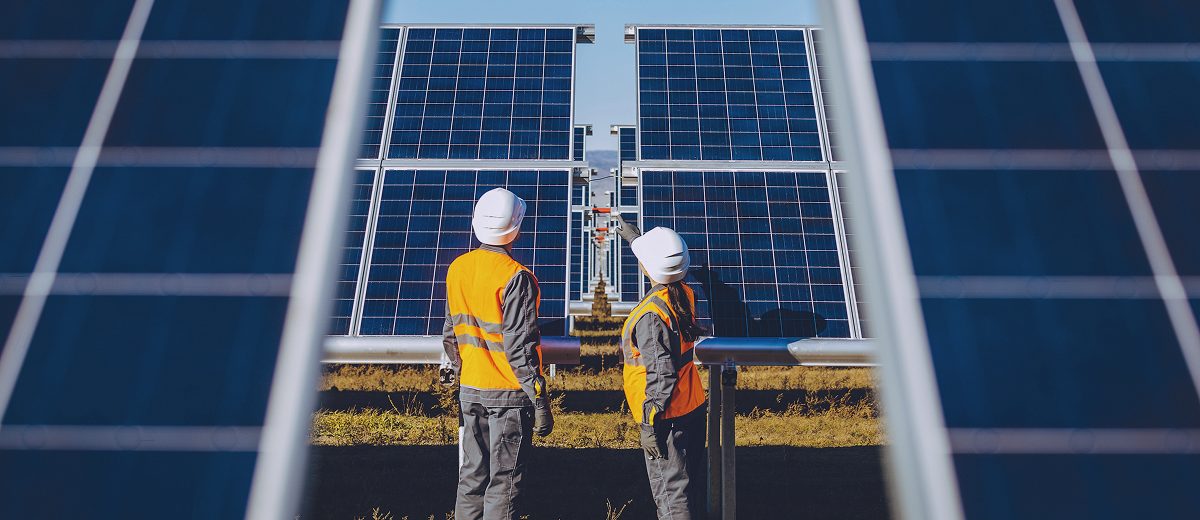 Technicians examining solar panels, highlighting the importance of specialized infrastructure in achieving renewable energy goals.
