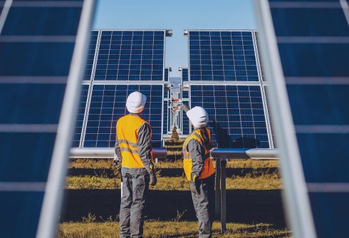 Technicians examining solar panels, highlighting the importance of specialized infrastructure in achieving renewable energy goals.
